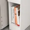 A close-up view of books on a shelf of a white nightstand. Produktbild-Vorschau
