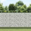 A gabion wall with plants and grass in front of it. Produktbild-Vorschau