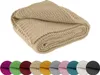 A folded beige knitted blanket is shown prominently, with a row of smaller circular swatches of various colored blankets below it. Náhled obrázku produktu