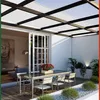 An outdoor patio area with a table and chairs under a modern pergola. Produktbild-Vorschau