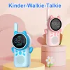 Two children's walkie-talkies, one blue and one pink, are displayed on decorative pedestals against a soft, pastel background. Produktbild-Vorschau