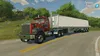 A red Mack truck pulling a white trailer drives on a paved road with green trees and a house in the background. Produktbild-Vorschau