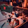 A workbench with various tools and small parts, including a black toolbox. Produktbild-Vorschau