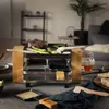 A raclette grill set up on a wooden table with food and accessories. Produktbild-Vorschau
