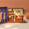 A miniature dollhouse tea room with detailed furniture and accessories, set against a plain background. Produktbild-Vorschau