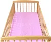 A pink crib sheet inside a wooden crib. Produktbild-Vorschau