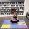 A woman is sitting on a colorful puzzle mat reading a book in front of a large bookshelf. Voir les images du produit