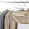 Three garments hanging on white hangers on a clothing rack. Produktbild-Vorschau