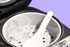 Close-up view of the interior of a Zojirushi rice cooker, showing a measuring cup and a rice paddle. Produktbild-Vorschau