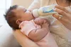 A person is feeding a baby with a bottle. Produktbild-Vorschau