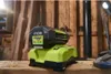 A Ryobi battery charger with a battery attached, placed on a wooden surface in what appears to be a workshop or shed. Anteprima dell’immagine prodotto