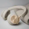 A pair of beige over-ear headphones with gold accents rests on a folded gray blanket. Náhľad obrázku produktu