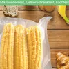 A flat lay of food items, including vacuum-sealed corn on the cob, bread, a banana, and a croissant, arranged on a wooden surface. Produktbild-Vorschau