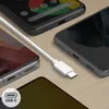A white USB-C cable is shown connecting to multiple smartphones on a wooden surface. Podgląd zdjęcia produktu