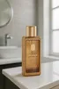 A gold-colored perfume bottle sits on a white countertop in a bathroom. Produktbild-Vorschau