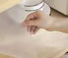 A hand is holding a textured, transparent mat over a wooden surface. Voir les images du produit