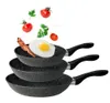 Three frying pans stacked on top of each other, with a fried egg, bacon, and some tomatoes and parsley floating above. Podgląd zdjęcia produktu