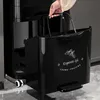 A hand is shown lifting a black trash can with a pedal, which is part of a multi-level trash can system. Produktbild-Vorschau