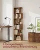 A corner of a room with a tall, s-shaped bookshelf filled with books and decorative items, next to a desk with a lamp and a clock. Produktbild-Vorschau