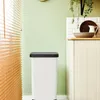 A white trash can with a black lid is placed in a kitchen setting next to wooden blinds and a cabinet. Produktbild-Vorschau