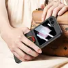 A person is holding a black phone case with a pink ring holder in front of a brown handbag. Produktbild-Vorschau
