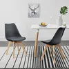 Two gray dining chairs with wooden legs are placed on a rug in front of a white dining table. Náhled obrázku produktu