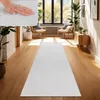 A hallway with a white runner rug, two chairs, a cabinet, and plants. Voir les images du produit