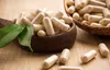 A close-up shot of herbal capsules in wooden bowls and scattered on a wooden surface. Produktbild-Vorschau