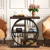 A narrow wooden side table with a circular metal frame shelf unit, placed between two tan armchairs in a living room setting. Anteprima dell’immagine prodotto