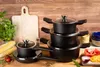 A set of cookware is arranged on a wooden surface with some fresh ingredients and a cutting board. Produktbild-Vorschau
