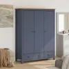 A blue wardrobe with a wooden top is shown in a bedroom setting, next to a bench with a blanket and a dresser with a mirror. Anteprima dell’immagine prodotto