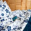 A bed with blue and white floral bedding and a book. Produktbild-Vorschau