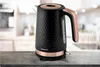 A black and copper electric kettle sits on a countertop in a kitchen setting. Náhled obrázku produktu