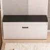 A white shoe cabinet with a black top is shown in a room with a striped wall and a rug on the floor. Podgląd zdjęcia produktu