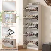 A tall, white shoe cabinet with multiple flip-out shelves filled with shoes, shown in a room setting with a plant and a wall. Produktbild-Vorschau