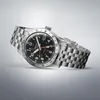 A silver Seiko 5 GMT watch with a black dial is displayed diagonally against a light gray background. Produktbild-Vorschau