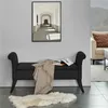 A black storage bench with a blanket and books on it, placed in a room with a framed picture on the wall and a sofa in the background. Podgląd zdjęcia produktu