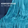 A teal colored blanket draped over a dark blue sofa. Náhľad obrázku produktu