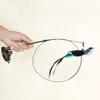 A hand holding a cat toy with a bird attached to a wire, which is attached to a suction cup. Voir les images du produit