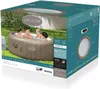 A box for a Lay-Z-Spa Palm Springs AirJet hot tub, showing a lifestyle image of people enjoying the spa in a garden setting. Produktbild-Vorschau