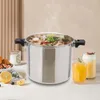 A large stainless steel pressure cooker filled with food, placed on a table with drinks and fruit. Podgląd zdjęcia produktu