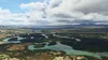 An aerial view of a winding river flowing through a lush green landscape with mountains in the distance. Produktbild-Vorschau