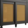 A close-up, low-angle shot of a dark-colored cabinet with two sliding doors made of woven rattan. Podgląd zdjęcia produktu
