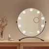 A makeup mirror with lights on a wooden dresser.