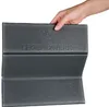 A hand holding a folded gray seat cushion. Produktbild-Vorschau