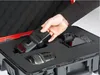 A hand places a camera flash into a foam-lined case with a camera and lens already inside. Anteprima dell’immagine prodotto