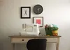 A sewing machine is set up on a desk with various crafting supplies. Produktbild-Vorschau