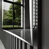 A close-up view of a modern bathroom mirror with integrated LED lighting, reflecting a window with greenery. Produktbild-Vorschau
