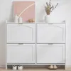 A white shoe cabinet with four flip-down compartments and gold handles is shown in a room. Produktbild-Vorschau