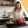 A woman is cooking in a modern kitchen on an induction cooktop. Voir les images du produit